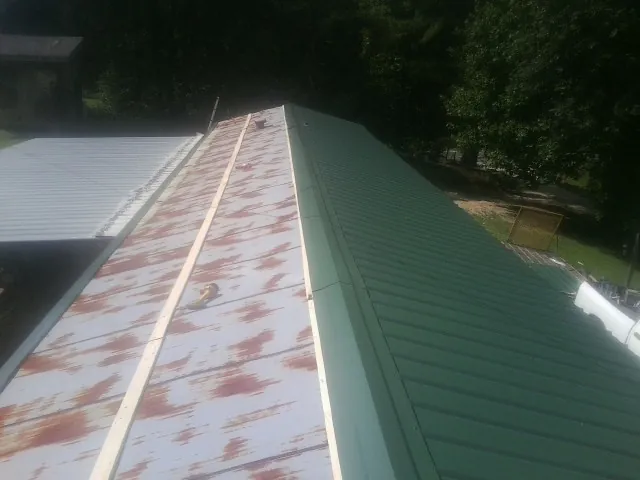 Old rusted panels beside newly installed green metal roofing — Wind Damage Roof Repair by Roofing Brothers in Cream Ridge