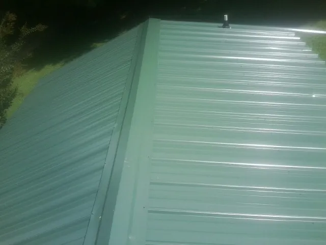 New green metal panels meeting at the ridge of a roof — Flat Roof Repair work by our crew in Cream Ridge