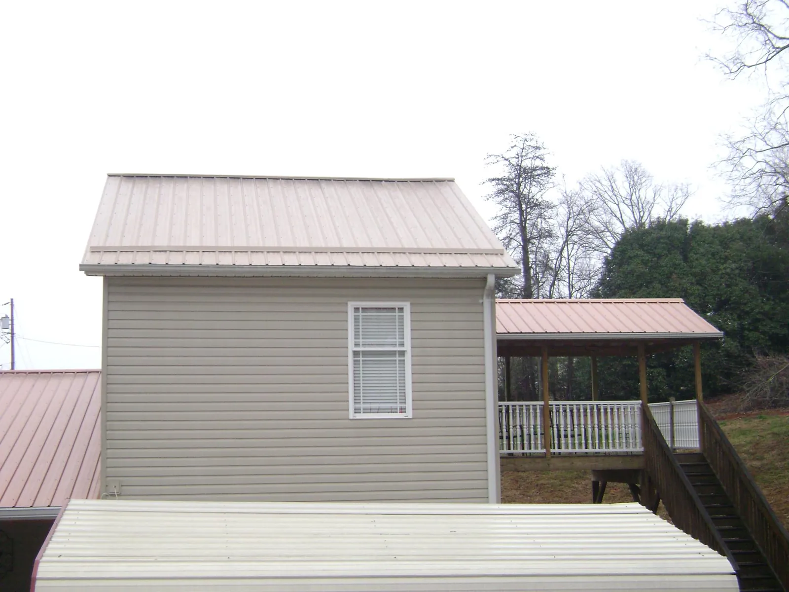 Tan metal roofs on a two story addition and attached porch, from a Roof Replacement job in Cream Ridge