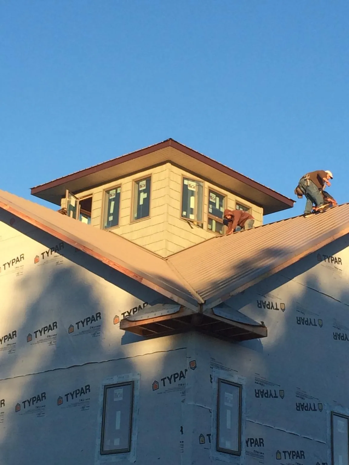 Roofers working around a rooftop cupola on a new metal roof at sunset — Roof Waterproofing in Cream Ridge by Roofing Brothers